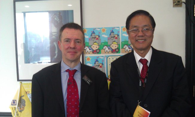 A photo of Mr． Howard Wang， President of CDIC （right） and Mr． Mark Neale ， Chief Executive of the Financial Services Compensation Scheme of United Kingdom， the conference host organization， taken in front of the CDIC’s exhibition desk of the International Deposit Insurance Exhibition．