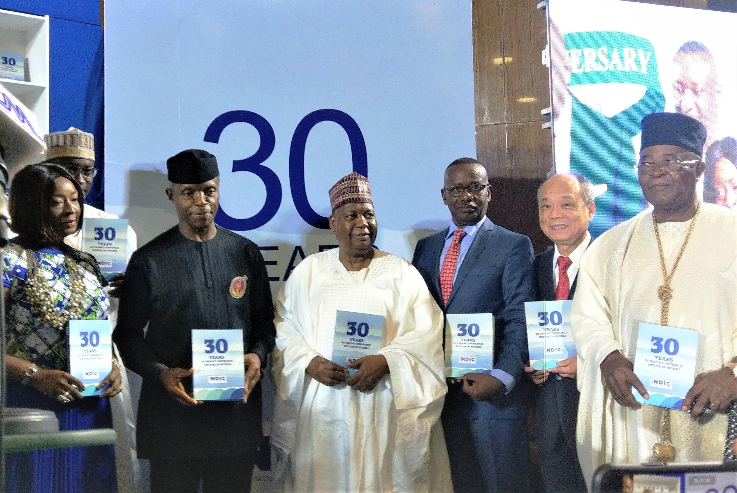 「奈及利亞存款保險制度30年回顧」專書發表嘉賓合照，包含奈國副總統Prof. Yemi Osinbajo（左2）、本公司董事長林銘寬（右2）、NDIC董事長Ronke Sokefun（左1）及其執行長Umaru Ibrahim（左3）